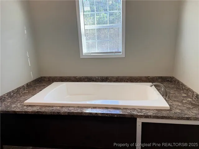 a bathroom with a granite countertop sink and a bathtub