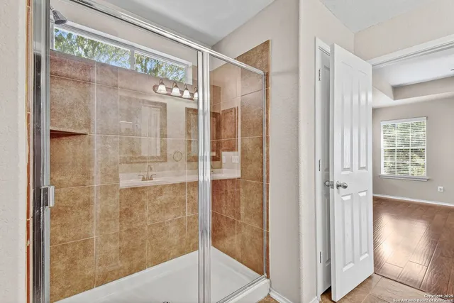 a bathroom with a glass shower door and a window