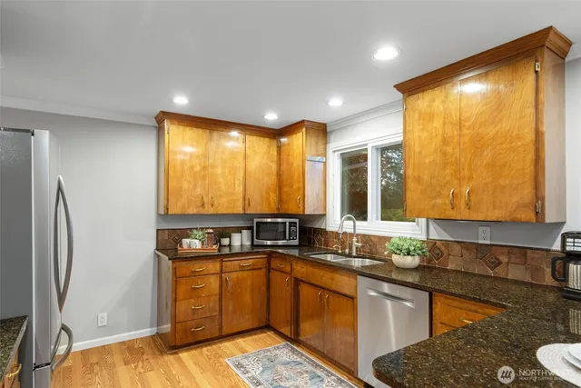 a kitchen with stainless steel appliances granite countertop a sink a stove and a refrigerator