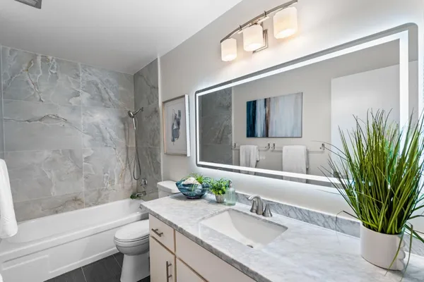 a bathroom with a granite countertop tub a sink and a large mirror