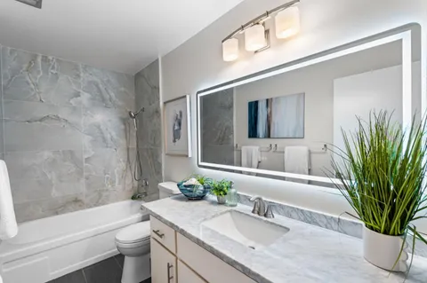 a bathroom with a granite countertop tub a sink and a large mirror