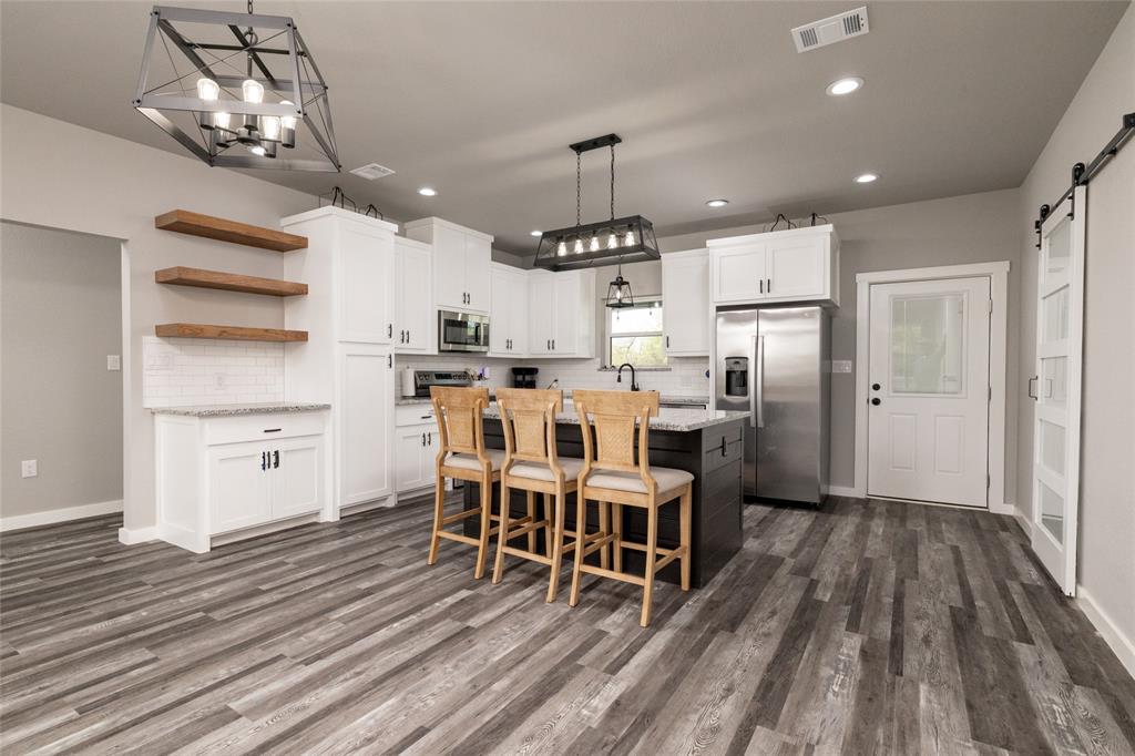 115 Valley Ridge Drive Bridgeport, TX 76426 - Photo 11 of 35 a kitchen with stainless steel appliances kitchen island granite countertop a table chairs refrigerator and microwave