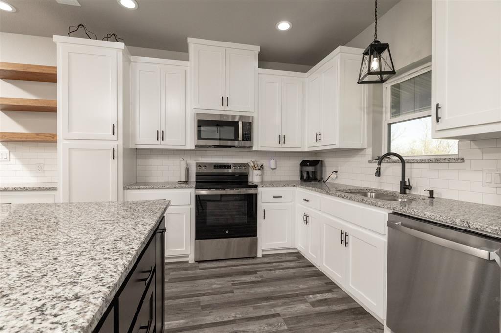 115 Valley Ridge Drive Bridgeport, TX 76426 - Photo 13 of 35 a kitchen with kitchen island granite countertop a sink stainless steel appliances and white cabinets