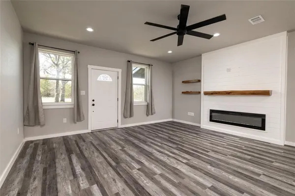 a view of empty room with wooden floor and fan