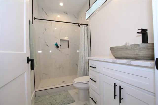 a bathroom with a granite countertop sink toilet and shower