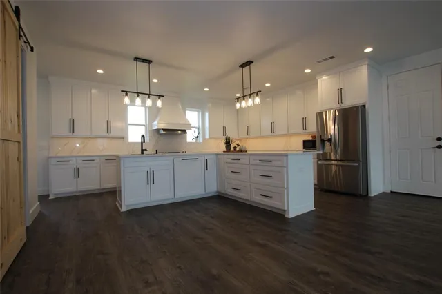 a kitchen with stainless steel appliances a sink cabinets and wooden floor