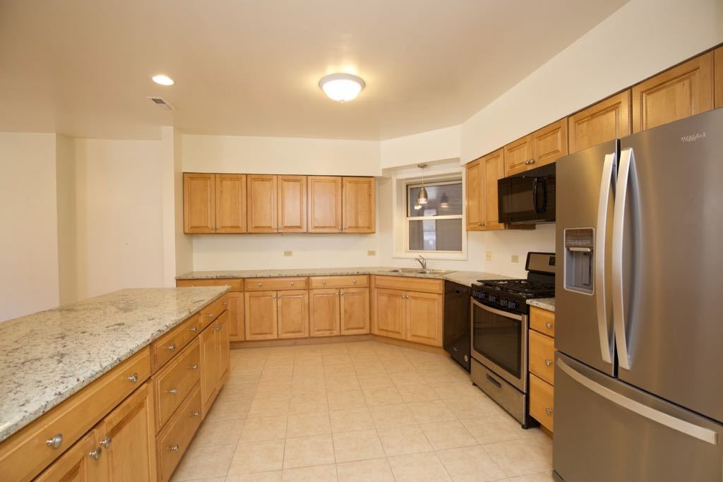 6713 North Sheridan Road, Unit 1N Chicago, IL 60626 - Photo 2 of 20 a large kitchen with kitchen island granite countertop a sink and stainless steel appliances