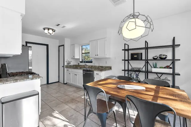 a kitchen with stainless steel appliances granite countertop a sink a stove a refrigerator a dining table and chairs with wooden floor