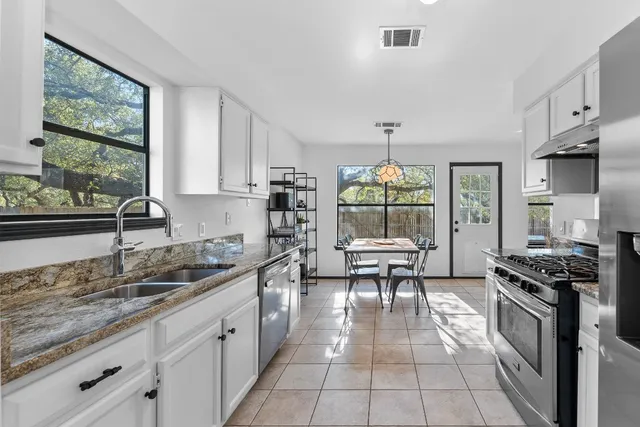 a kitchen with granite countertop a stove a sink and a wooden cabinets