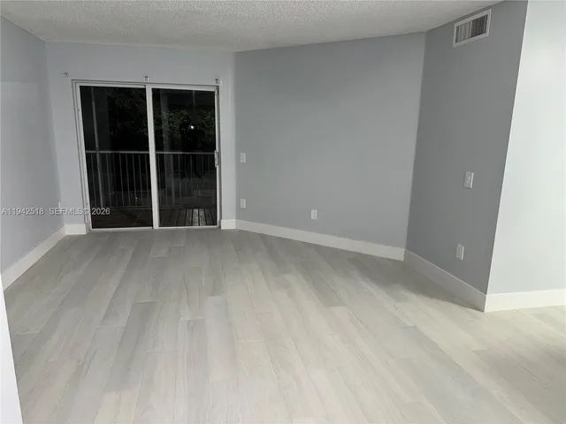 a view of an empty room with cabinet and wooden floor
