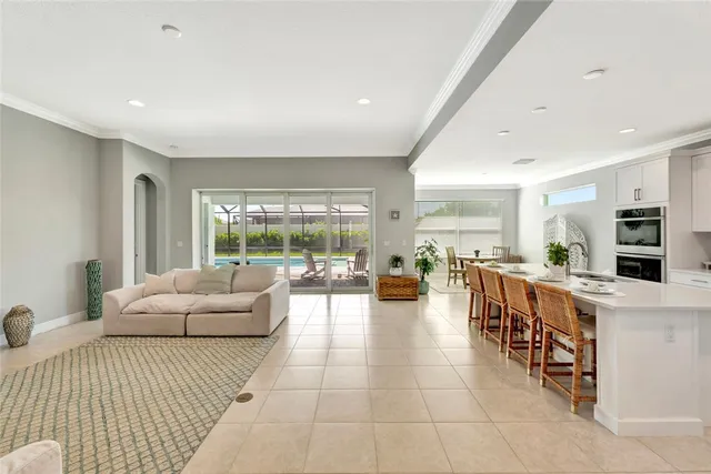 a large living room with stainless steel appliances furniture a large window and a chandelier