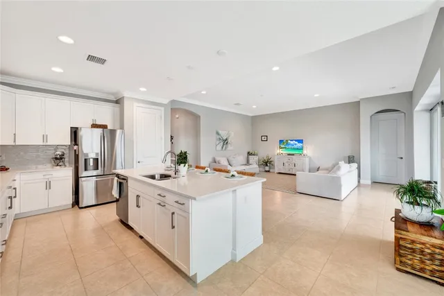 a large white kitchen with cabinets a sink a window and stainless steel appliances