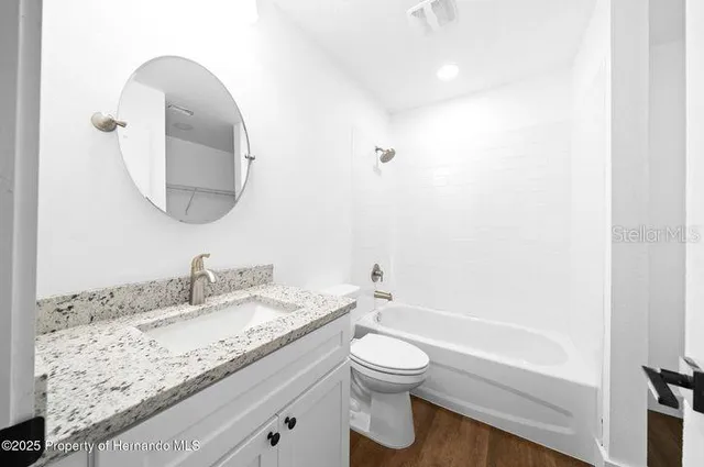 a bathroom with a granite countertop sink a toilet and a bathtub