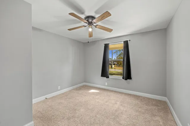 an empty room with window and ceiling fan