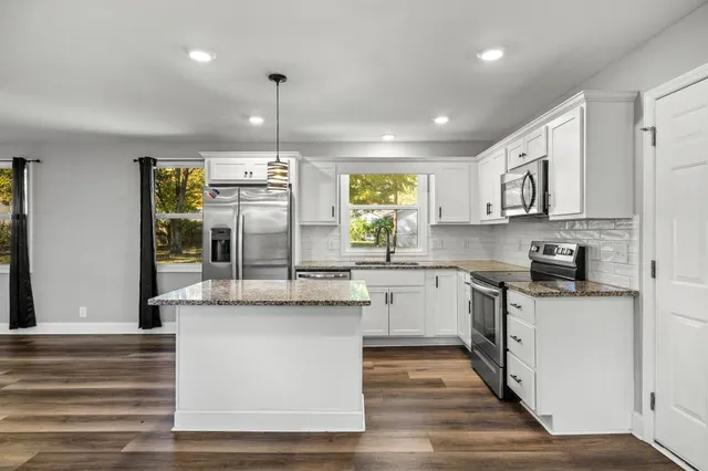 a kitchen with kitchen island granite countertop a sink cabinets and stainless steel appliances