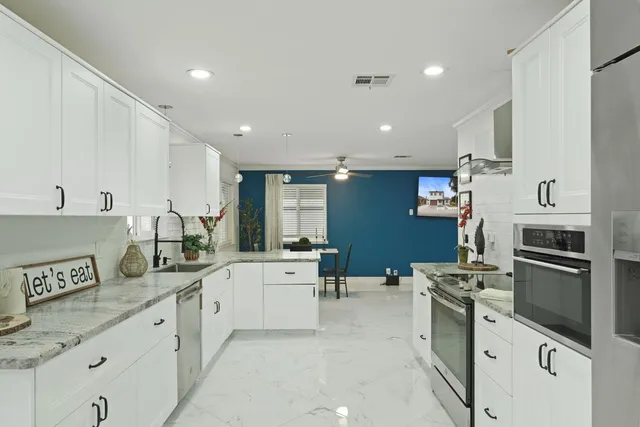 a large white kitchen with stainless steel appliances and a sink