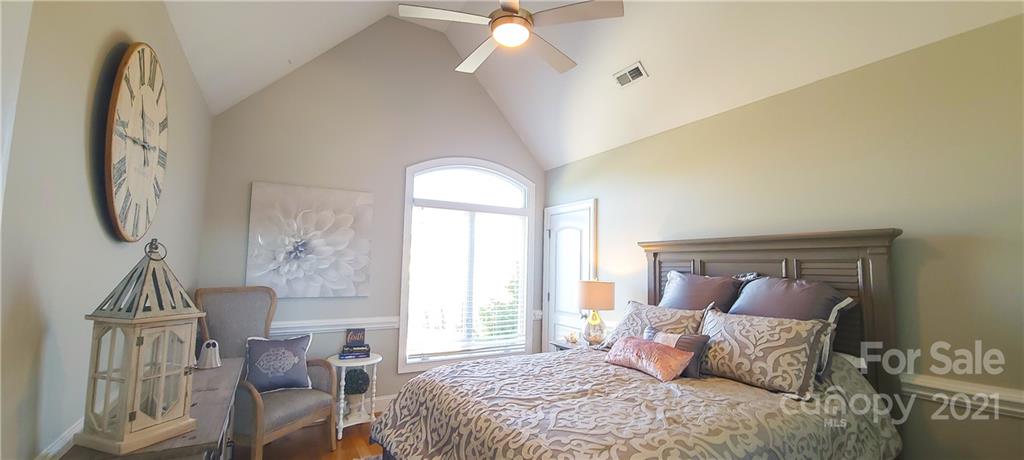 140 Rocky River Road Mooresville, NC 28115 - Photo 14 of 32 a bedroom with a bed a mirror on dresser and a chandelier