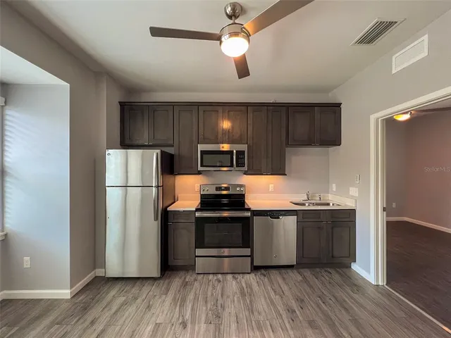 a kitchen with stainless steel appliances a refrigerator a sink a stove a microwave and wooden floor