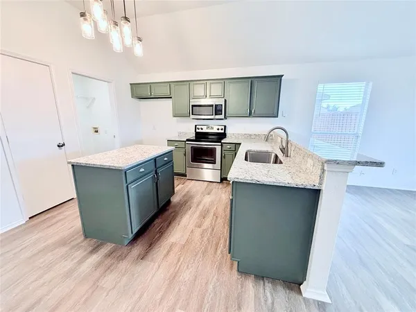 a kitchen with a sink cabinets and wooden floor