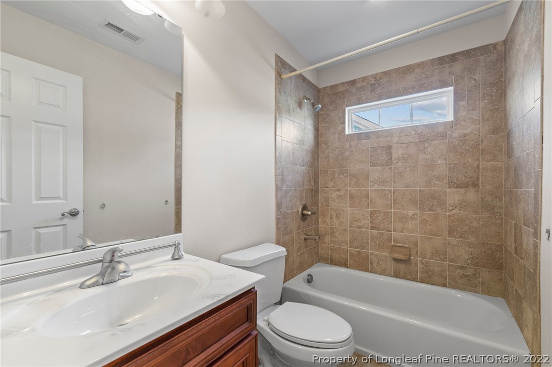 287 Falling Water Road Spring Lake, NC 28390 - Photo 23 of 24 a bathroom with a bathtub shower sink vanity mirror and toilet