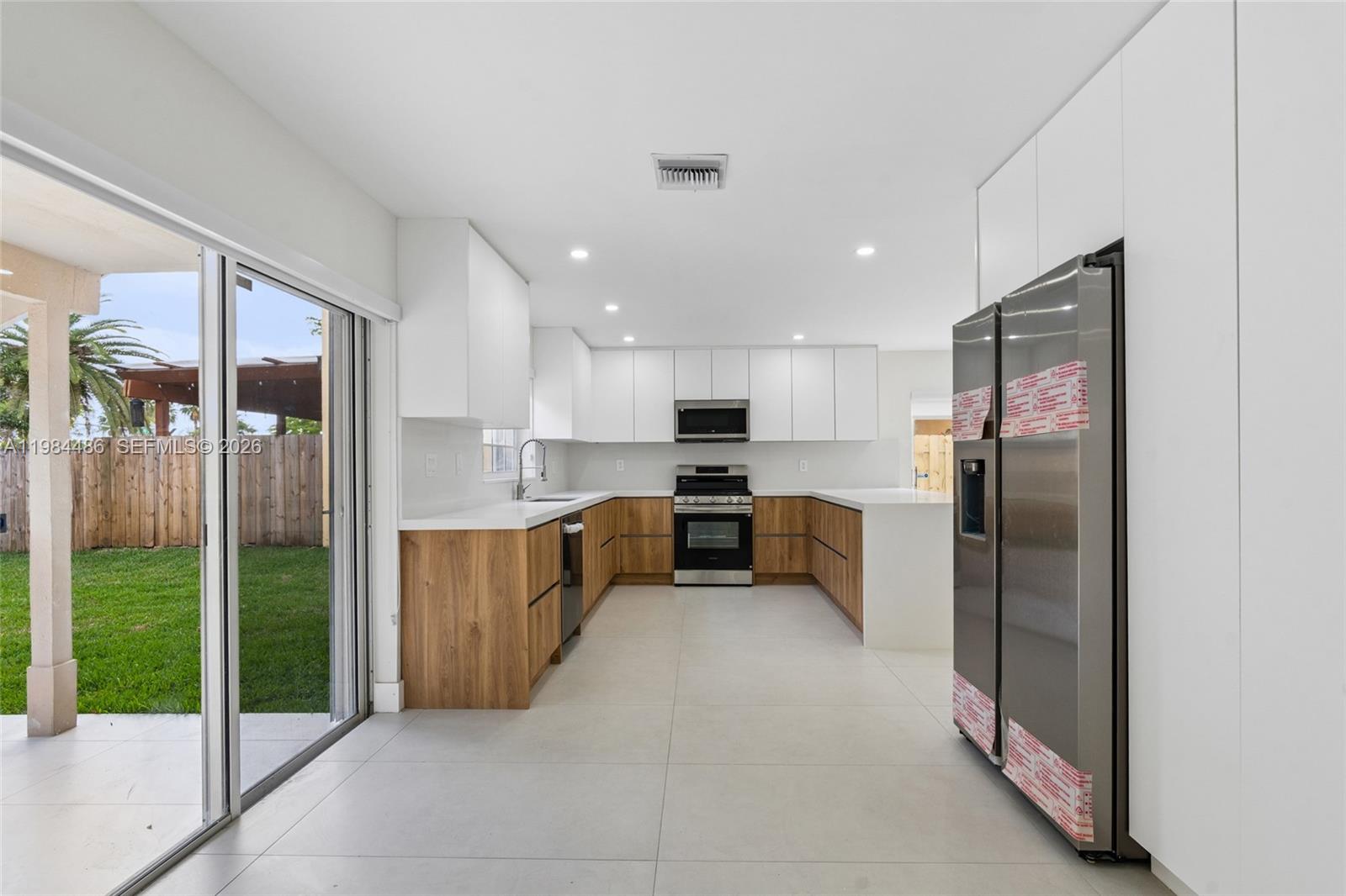 15174 Southwest 111th Street Miami, FL 33196 - Photo 13 of 49 a large kitchen with stainless steel appliances kitchen island granite countertop a refrigerator and a sink