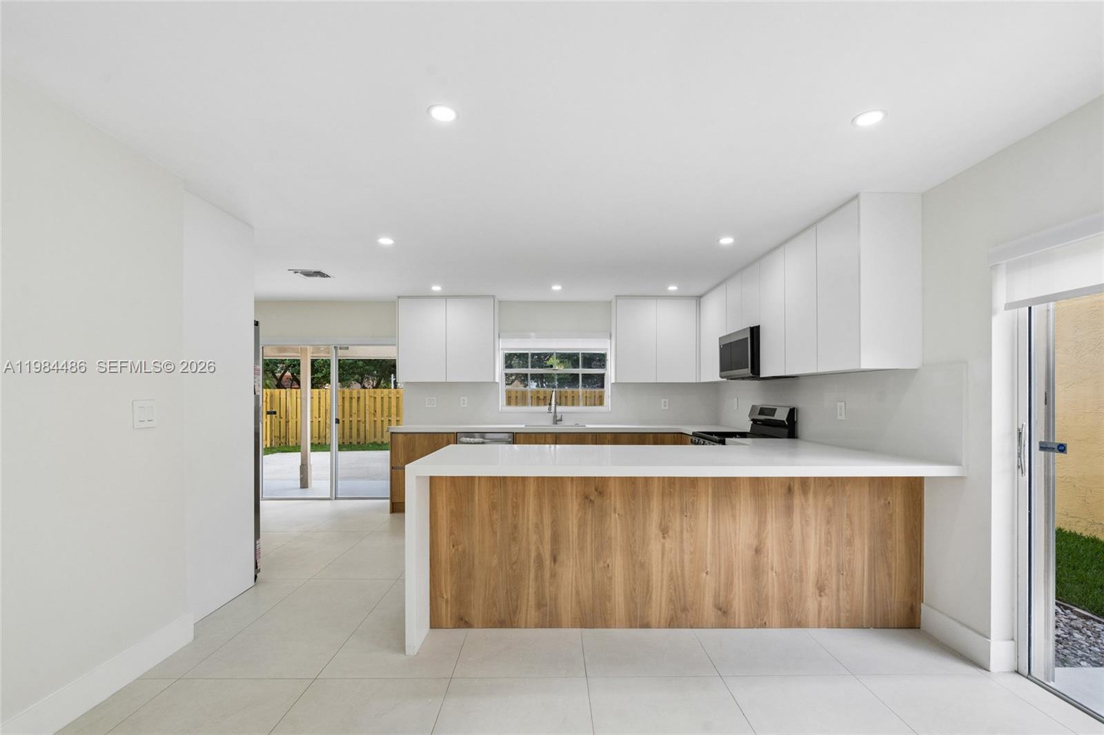 15174 Southwest 111th Street Miami, FL 33196 - Photo 9 of 49 a large kitchen with kitchen island a stove a sink a refrigerator and a dining table with wooden floor
