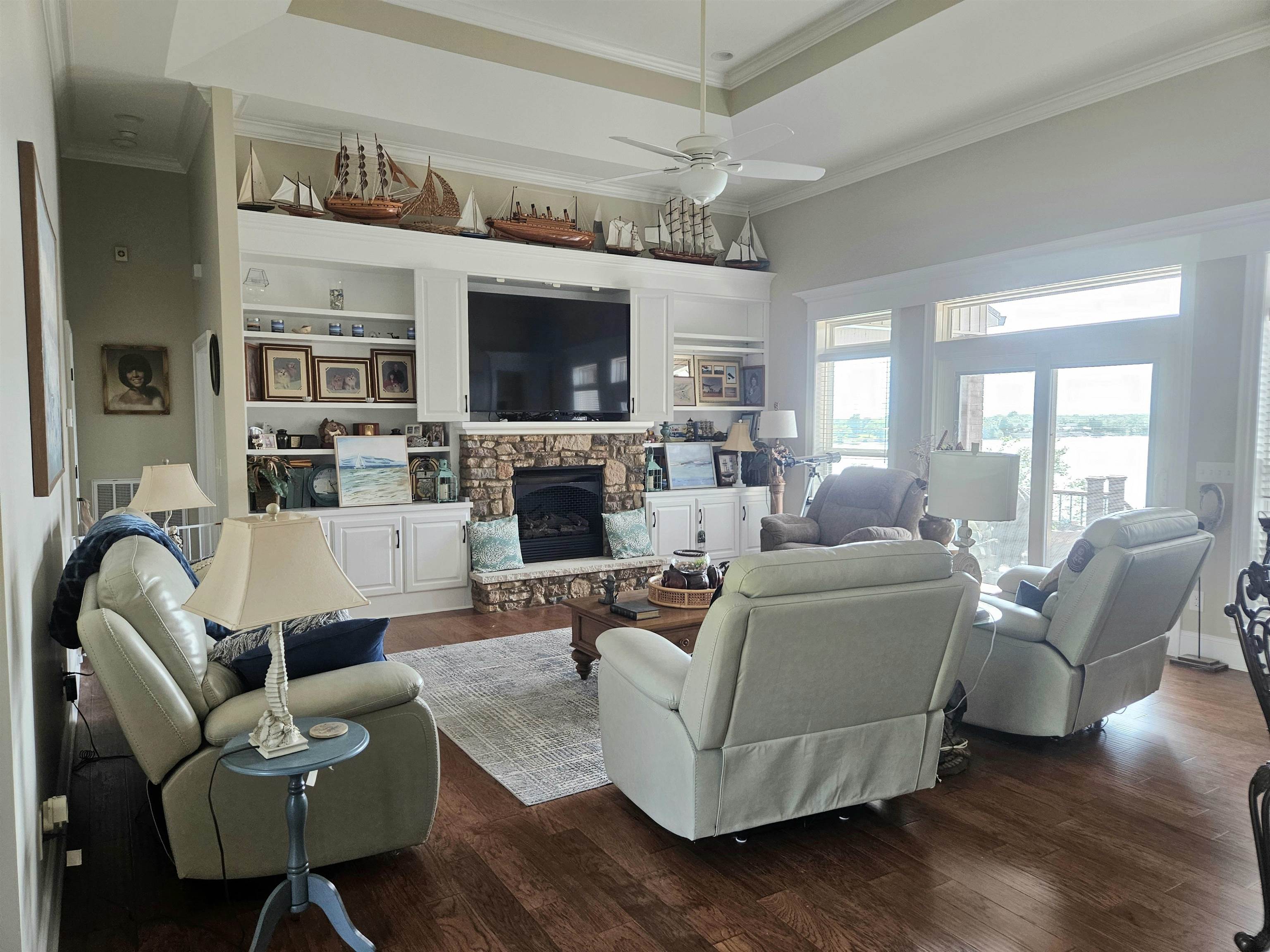 7095 Clifton Road Savannah, TN 38372 - Photo 8 of 25 Living area featuring a stone fireplace, crown molding, dark wood finished floors, and a ceiling fan