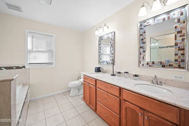a spacious bathroom with a double vanity sink a toilet and a mirror