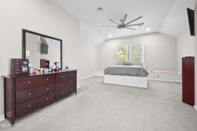 a spacious bedroom with a bed and a mirror on dresser
