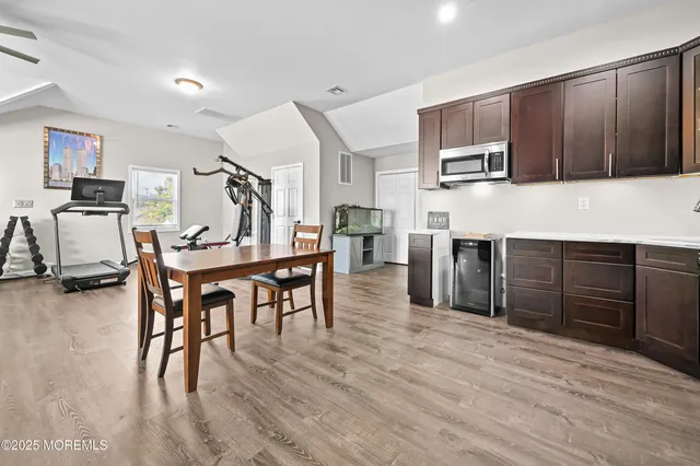 a kitchen with stainless steel appliances kitchen island granite countertop a table chairs and a refrigerator