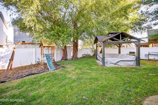 a view of a backyard with table and chairs a fire pit and large trees