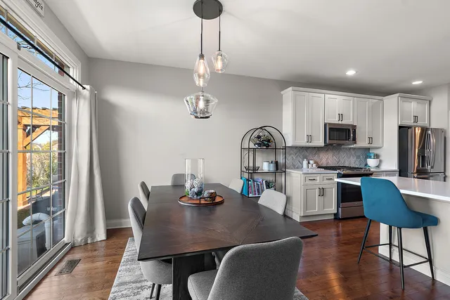 a kitchen with stainless steel appliances granite countertop a dining table chairs stove and refrigerator