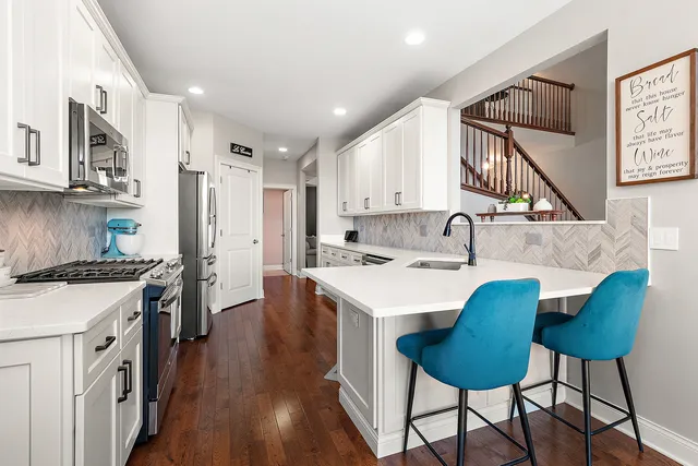 a kitchen with stainless steel appliances kitchen island a table chairs refrigerator and cabinets