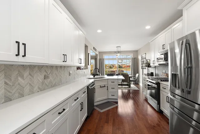 a kitchen with stainless steel appliances a refrigerator a stove a sink dishwasher a oven with white cabinets and wooden floor