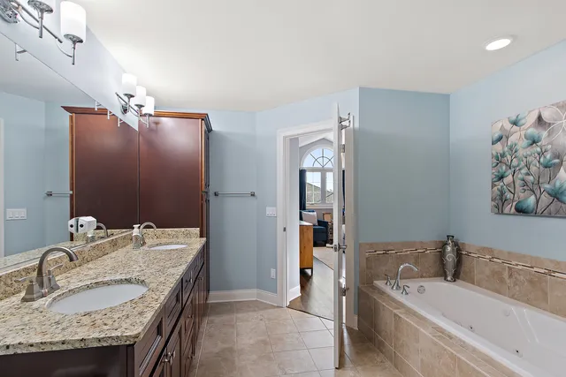 a bathroom with a granite countertop tub sink and mirror
