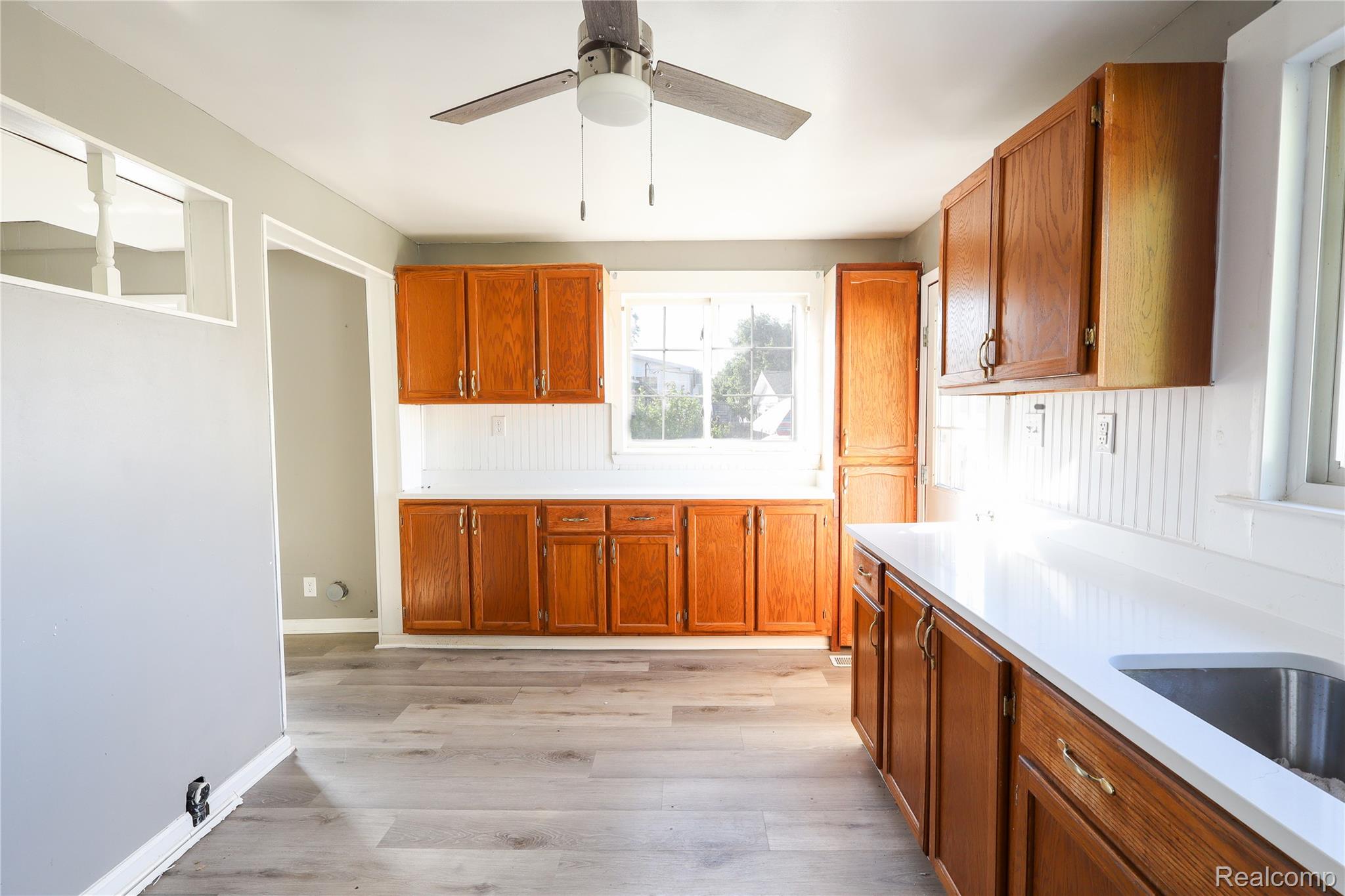 3319 Lakeview Street Monroe, MI 48162 - Photo 9 of 21 Kitchen featuring wood cabinetry, white countertops, stainless steel sink, beadboard backsplash, and wood-finish flooring