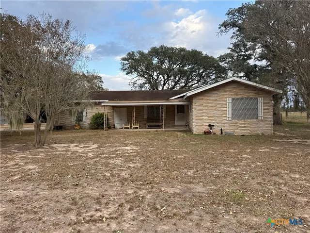 a front view of house with yard and trees around