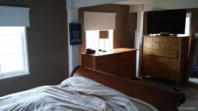 a bedroom with a bed and a flat tv screen on dresser