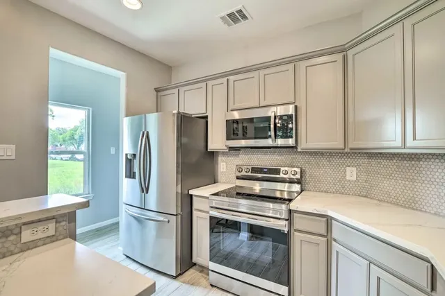 a kitchen with stainless steel appliances white cabinets and a stove top oven
