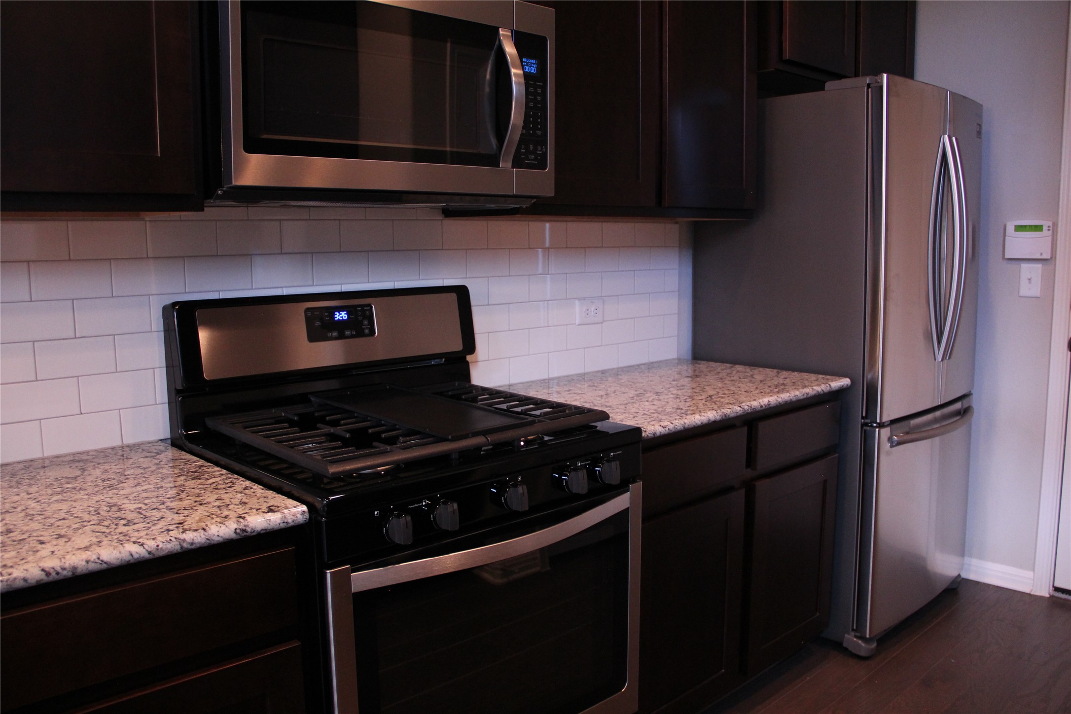 1612 Airedale Road Austin, TX 78748 - Photo 8 of 21 Kitchen featuring stainless steel appliances, dark wood finish cabinets, decorative backsplash, light stone countertops, and dark wood-style floors