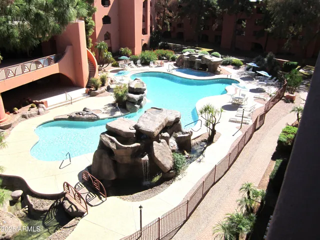 a couple of blue chairs sitting on a swimming pool with a yard