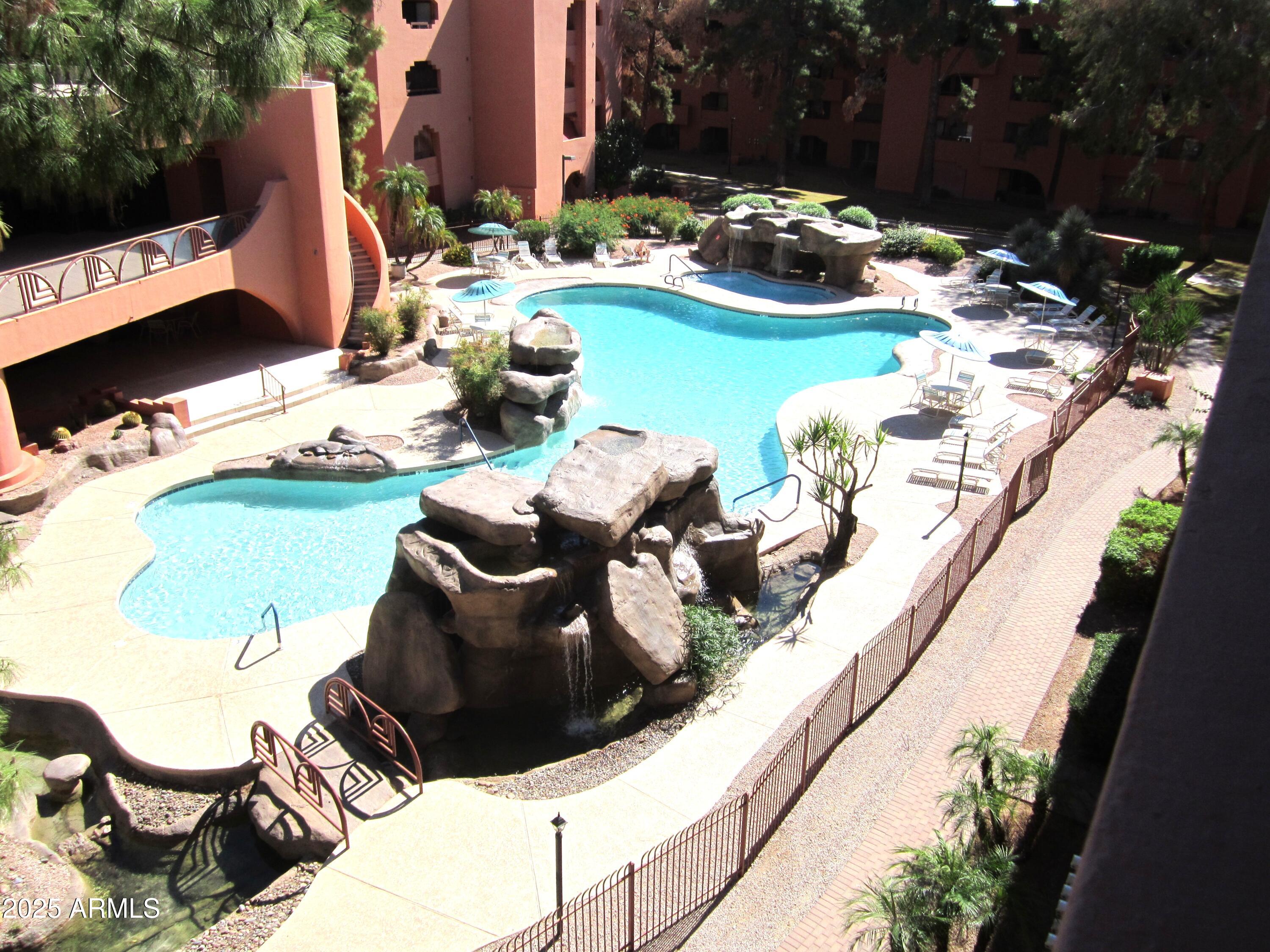 4303 East Cactus Road, Unit 407 Phoenix, AZ 85032 - Photo 16 of 16 a couple of blue chairs sitting on a swimming pool with a yard