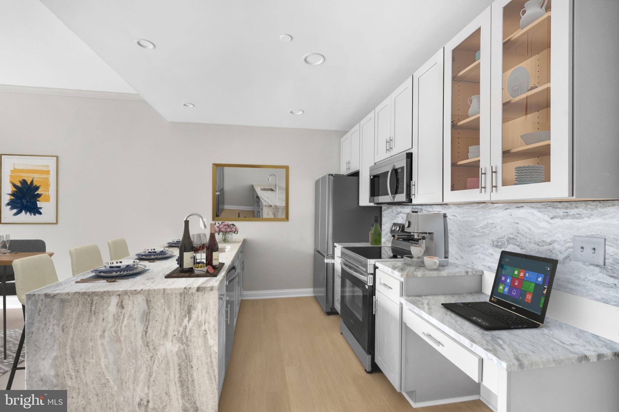 2301-61 John F Kennedy Boulevard, Unit 507 Philadelphia, PA 19103 - Photo 15 of 39 a kitchen with stainless steel appliances kitchen island granite countertop a stove top oven a sink a refrigerator and white cabinets with wooden floor
