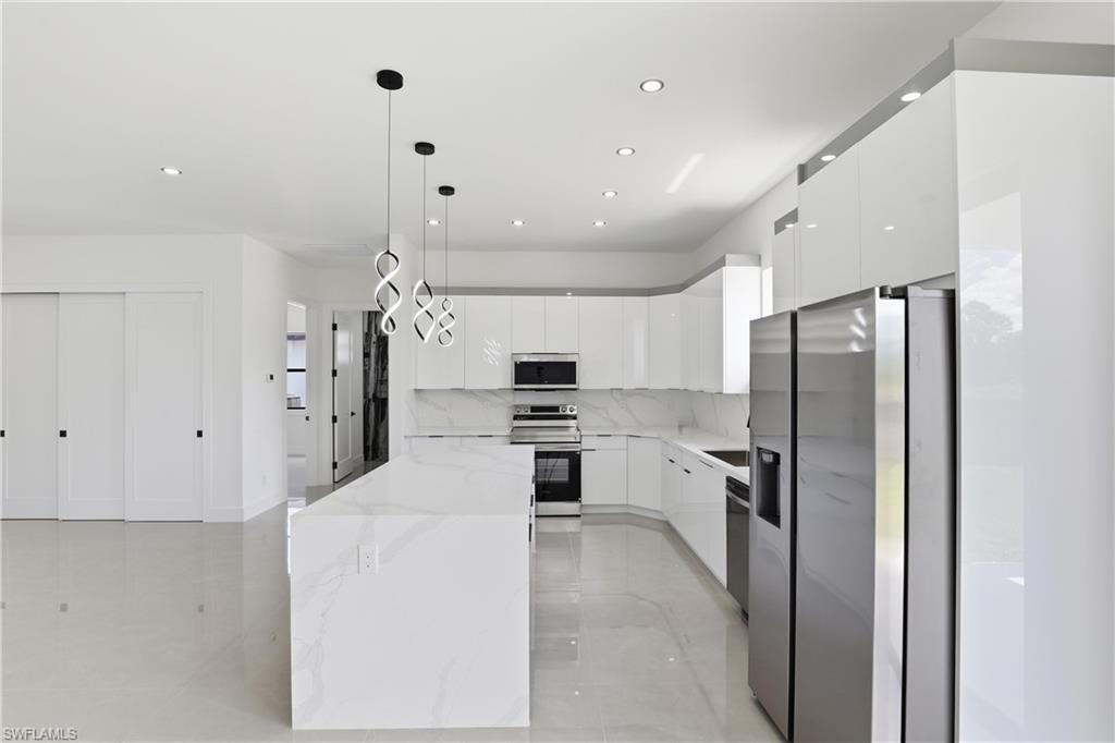 1122 Edelweiss Street East Lehigh Acres, FL 33974 - Photo 12 of 27 a kitchen with stainless steel appliances kitchen island a refrigerator and a stove top oven