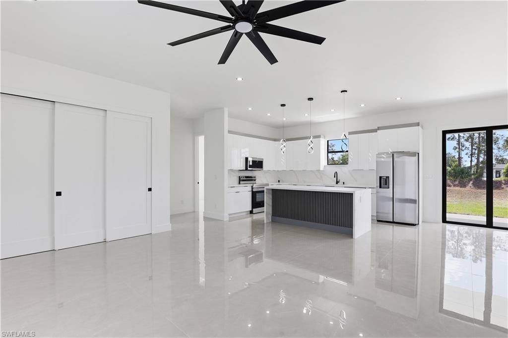 1122 Edelweiss Street East Lehigh Acres, FL 33974 - Photo 8 of 27 a large white kitchen with a sink stainless steel appliances and cabinets