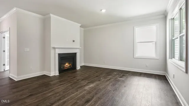 an empty room with wooden floor a fireplace and windows
