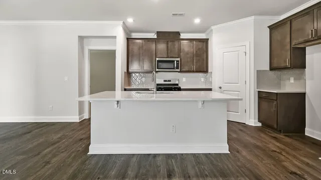 a large kitchen with stainless steel appliances a large counter top a stove and a refrigerator