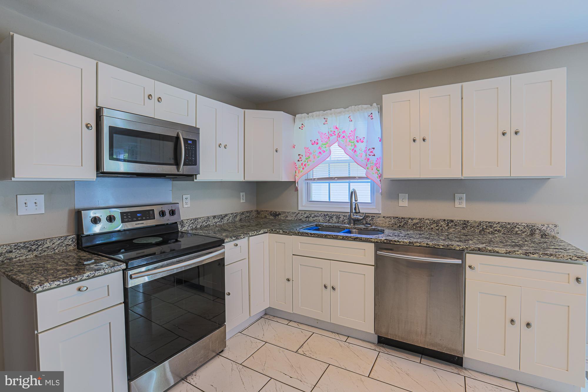 7933 34th Street Rosedale, MD 21237 - Photo 13 of 32 a kitchen with granite countertop white cabinets stainless steel appliances and a sink