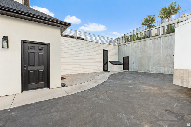 912 North Loafer Canyon Road Elk Ridge, UT 84651 - Photo 74 of 98 Paved outdoor space with a concrete pathway, white siding, and a dark entry door with exterior lighting
