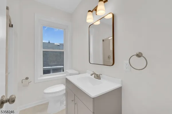 a bathroom with a sink vanity granite toilet and a mirror
